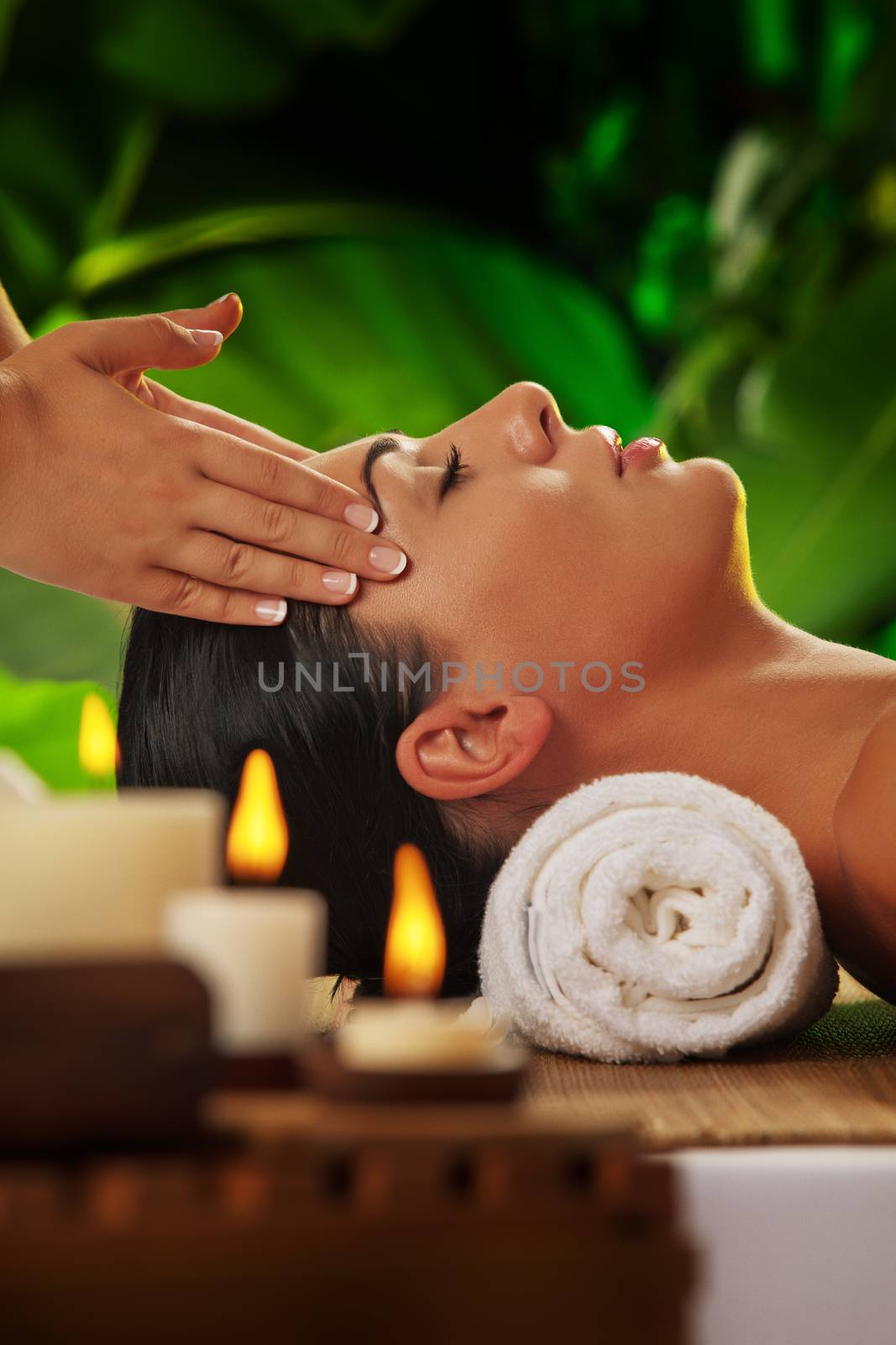 portrait of young beautiful woman in spa environment. blurred face, focused on candles