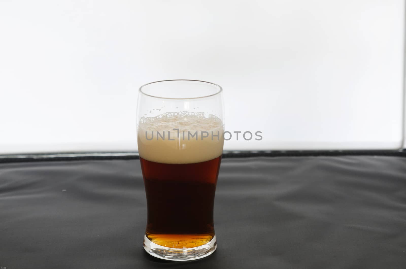 one glass of coold and dark beer ready to drink