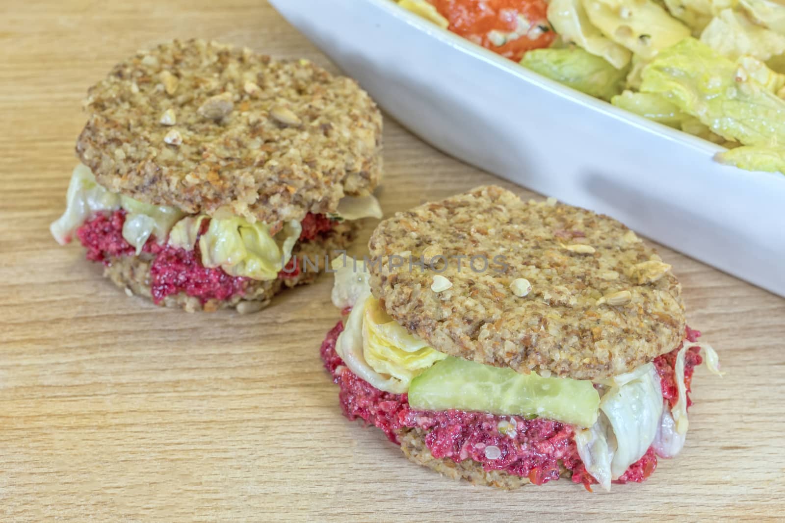 Raw burgers with beetroot and salad on a wooden background