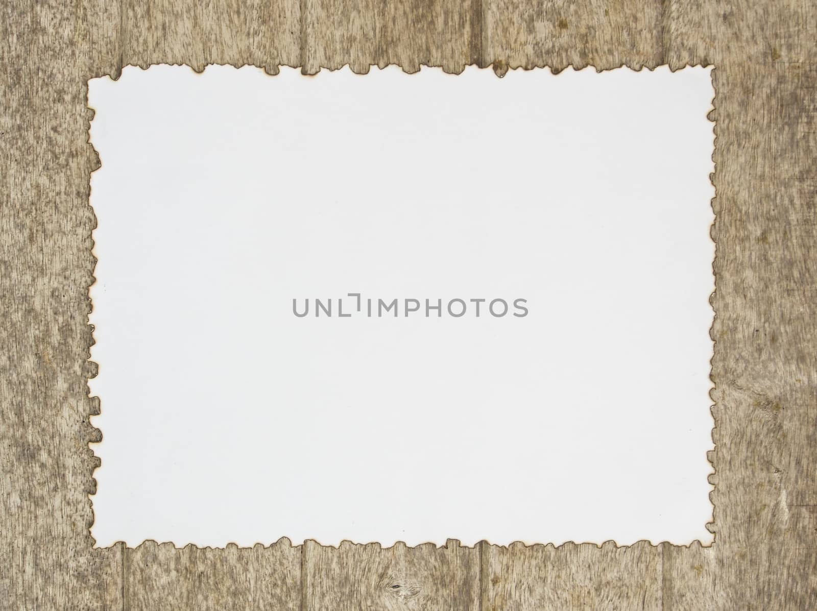 Burning the edges of white paper placed on a wooden background.
