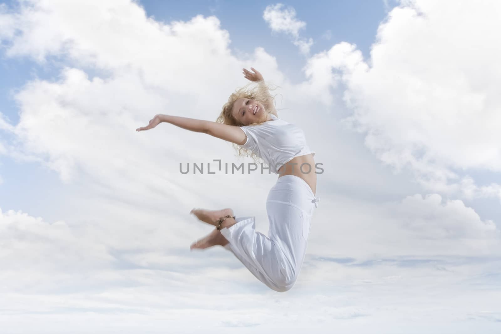 Portrait of young jumping woman on blue sky background