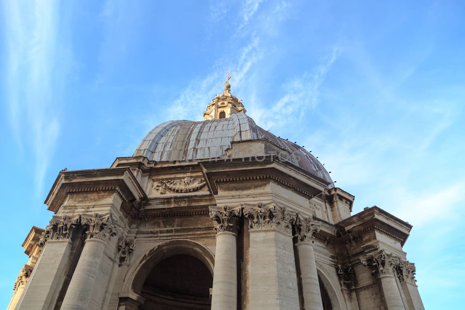 Close up detailed dome view of Saint Peter's Basilica in Vatican, on cloudy blue sky background.