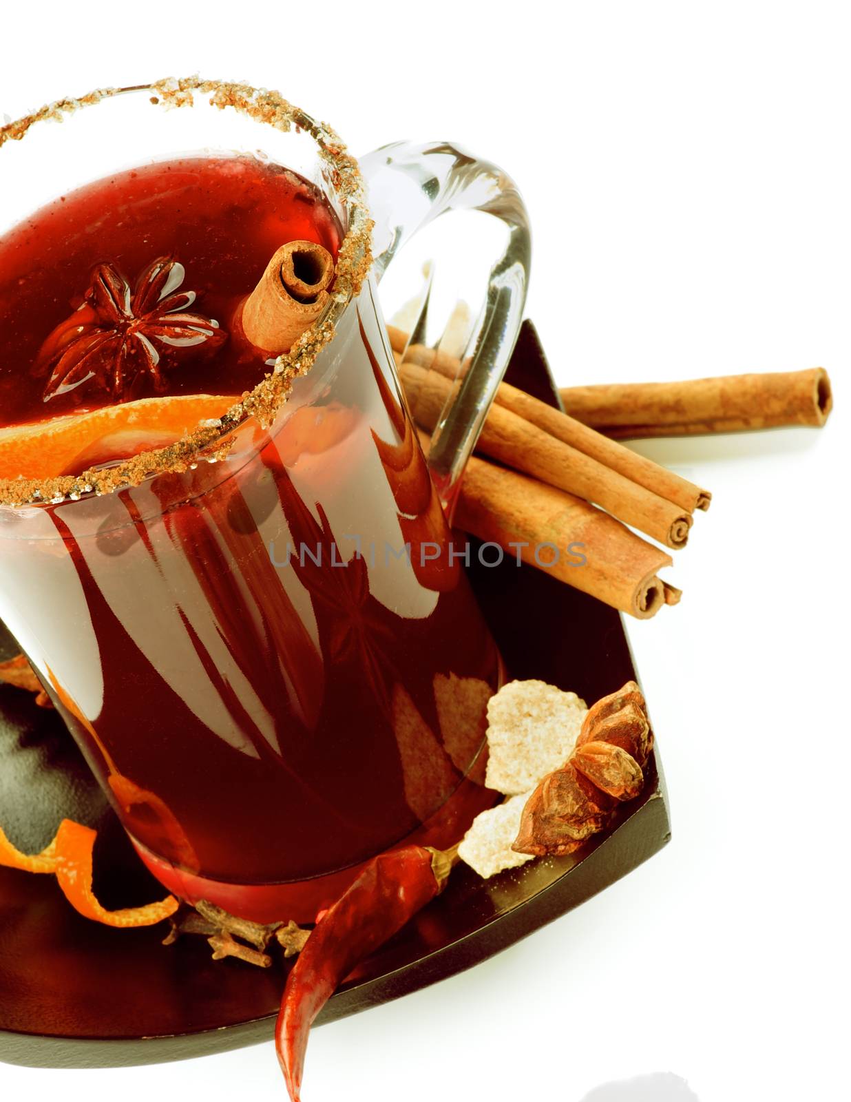Glass Cup of Mulled Wine with Cinnamon Stick, Slice of Orange and Spices on Black Saucer closeup on White background
