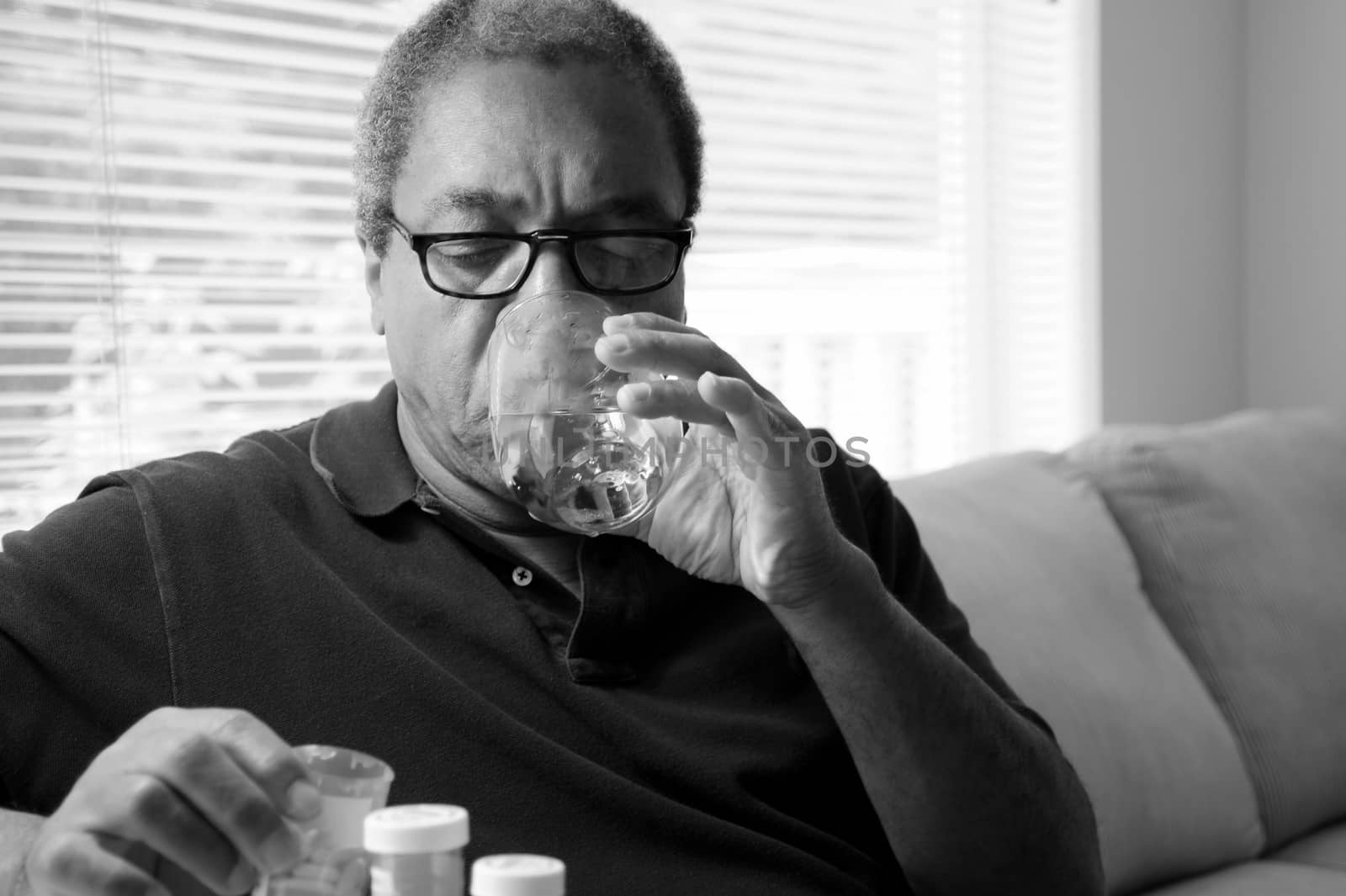 African american male taking his blood pressure medication at home.