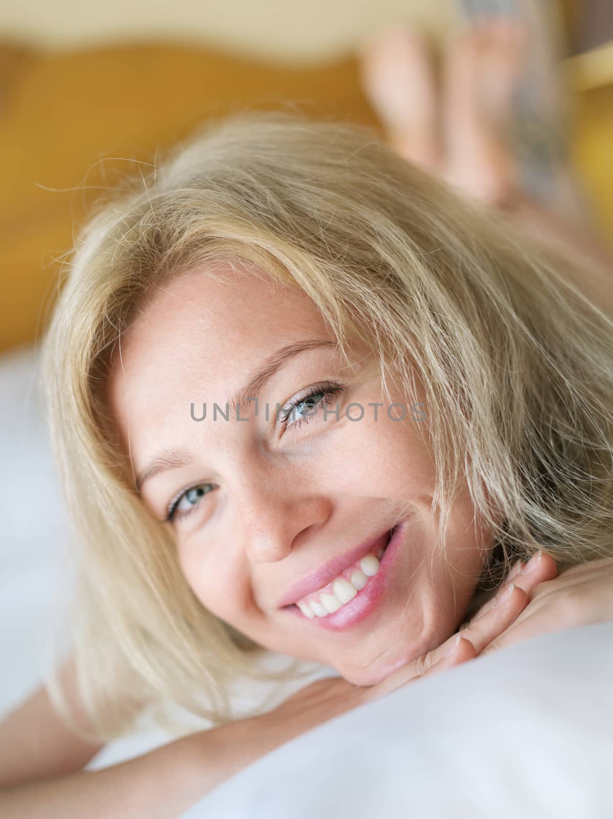 portrait on gorgeous young smiling woman in bedroom environment