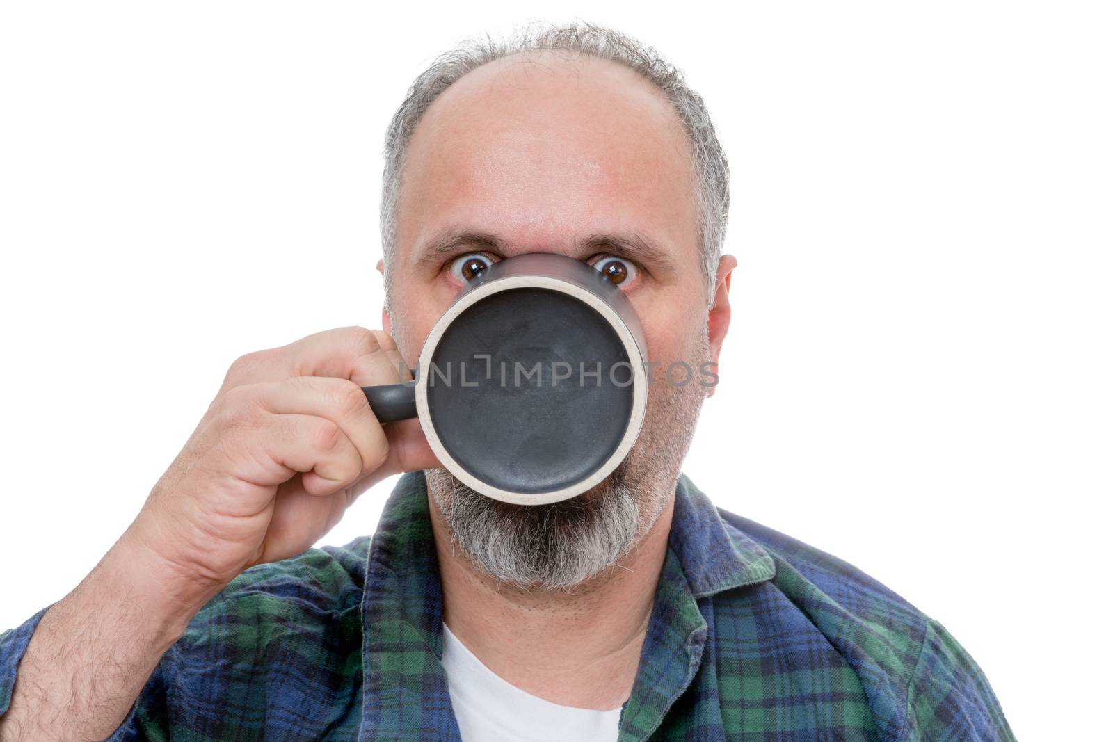 Single balding and bearded shocked man drinking from a dark coffee mug with wide open eyes over white background