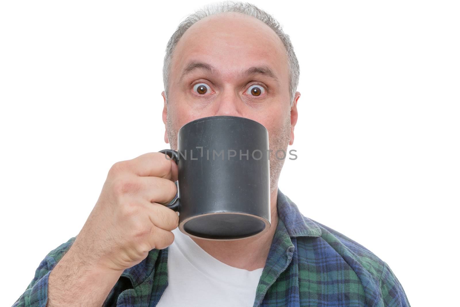 Single balding and bearded shocked man holding dark coffee mug in front of face with wide open eyes over white background