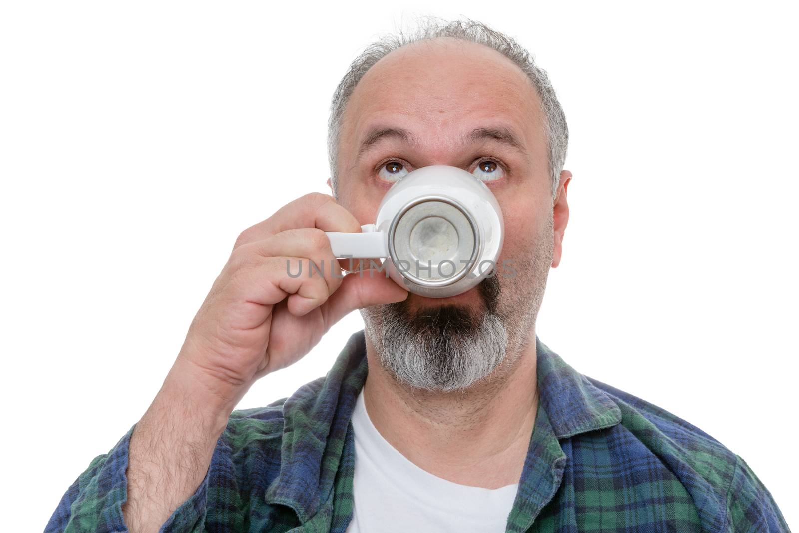 Single bearded man in flannel shirt looking upward while drinking his morning coffee from a white mug