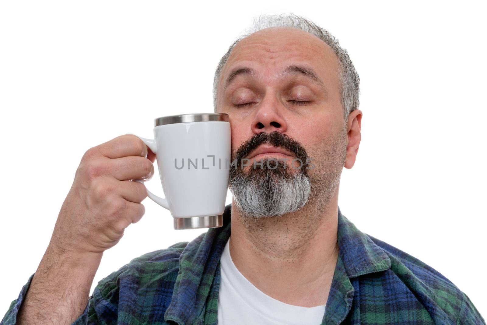 Sleepy middle aged man with receding hairline and beard struggling to bring a coffee mug to his mouth after awakening