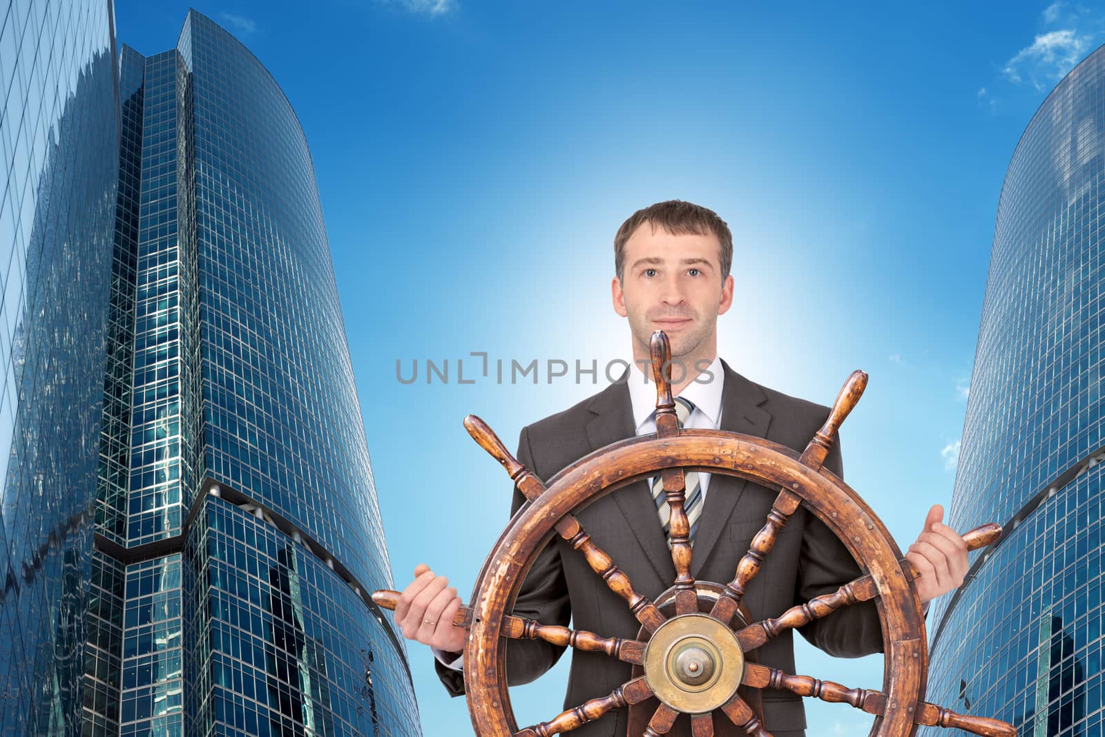 Businessman holding steering wheel with cityscape, travel concept