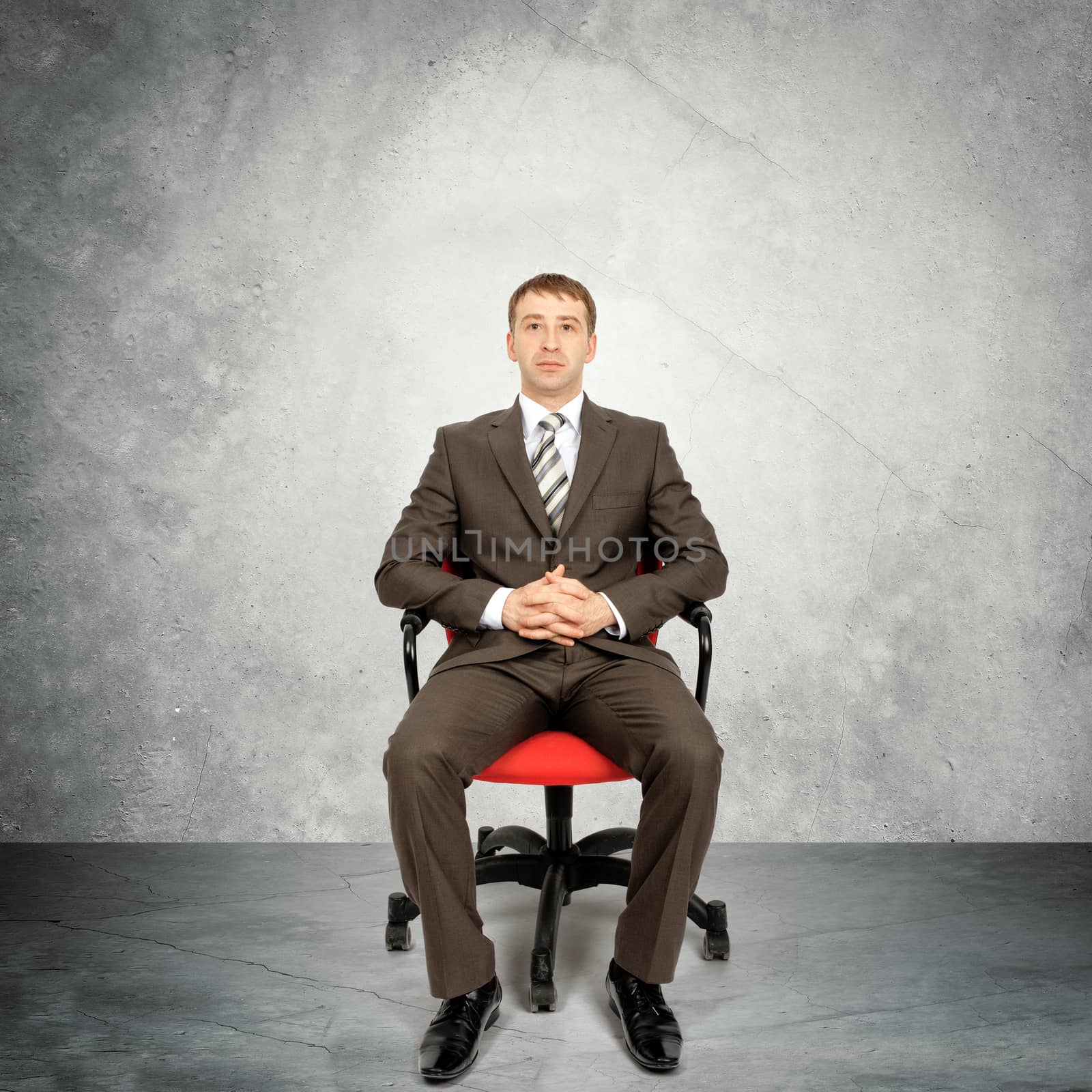 Businessman sitting in chair on grey wall background, business concept