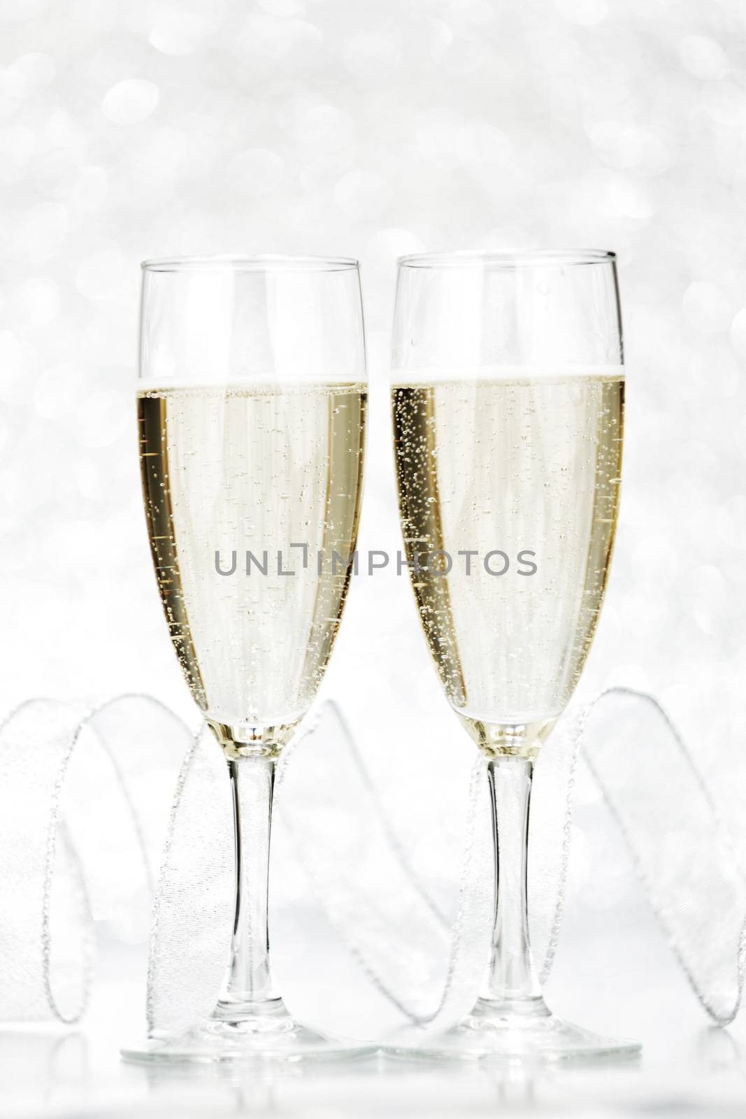 Two glasses of champagne with bow on silver background