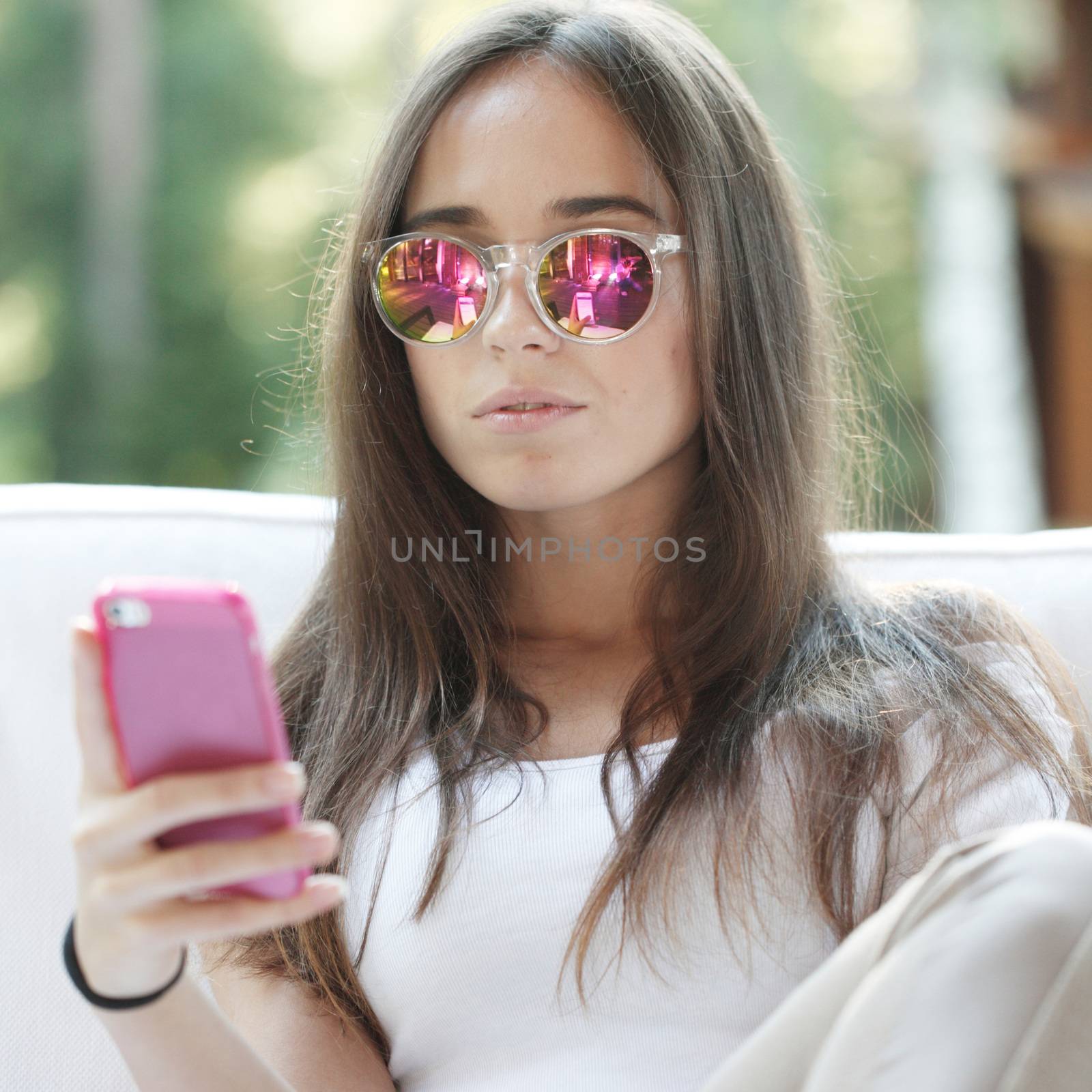 Beautiful young girl with smartphone sitting outdoors