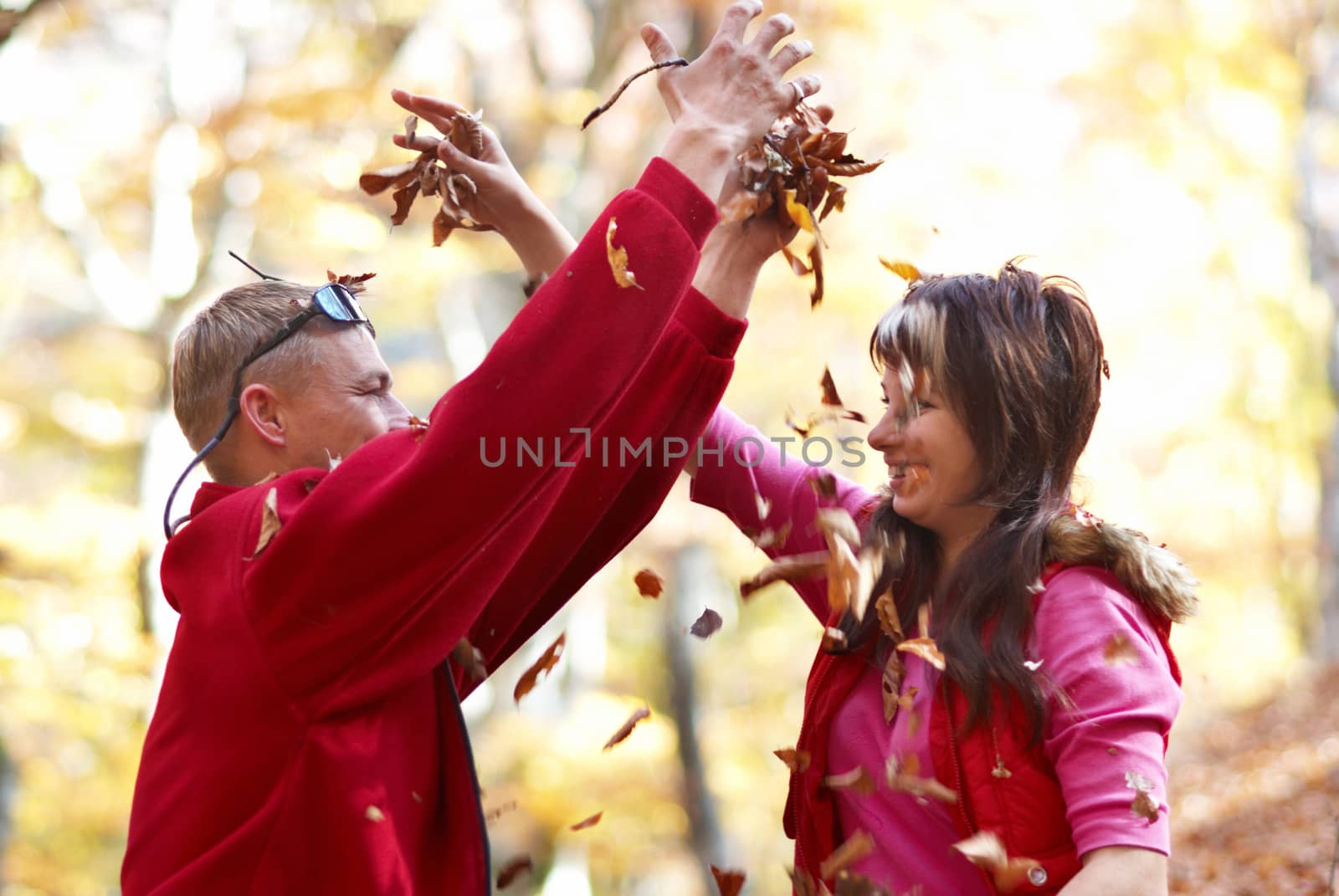 Young couple enjoying the falling leaves in the autumn park