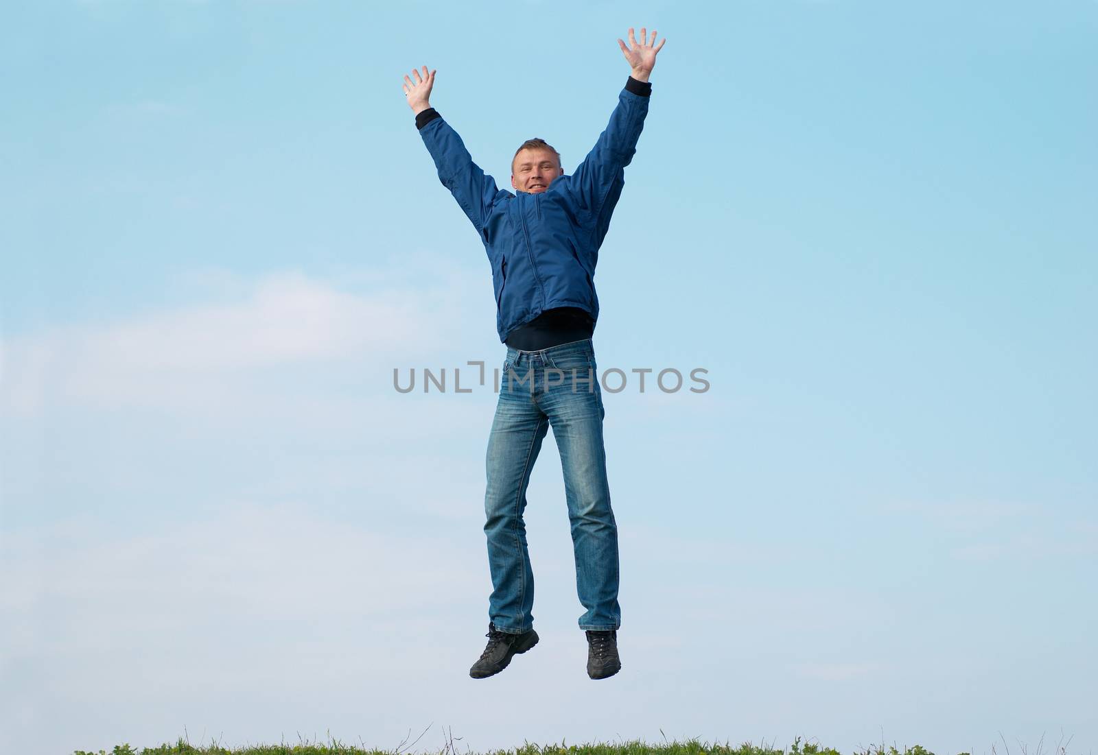 Jumping man on the hill with green grass