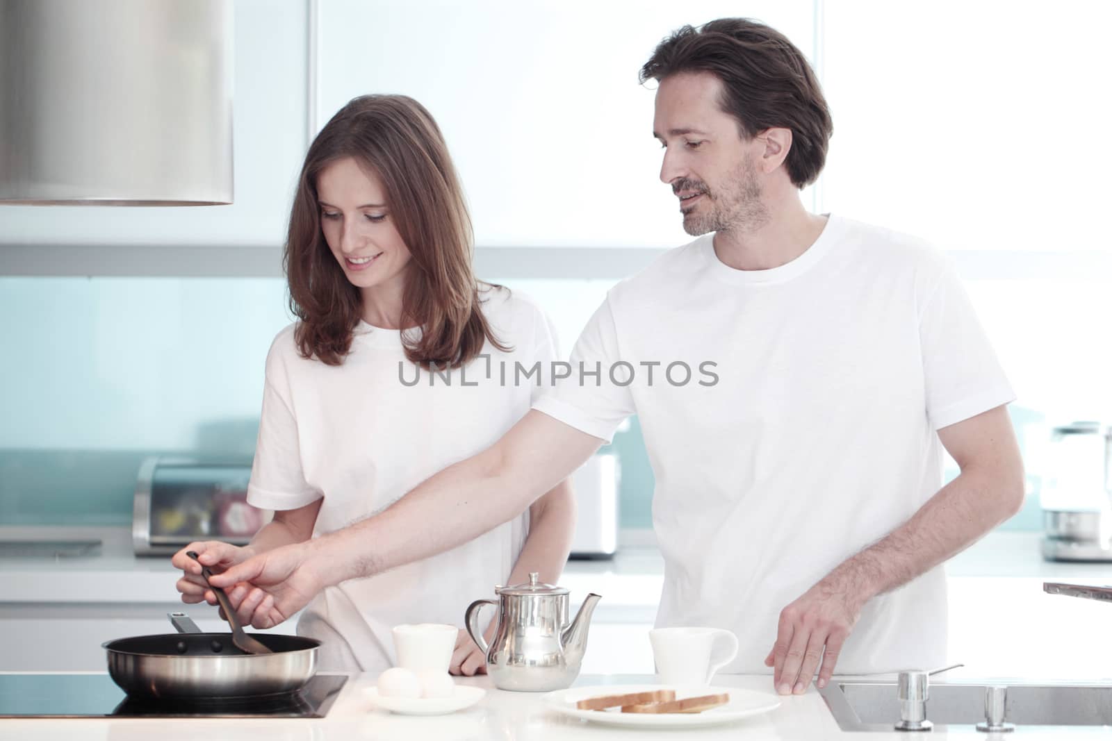 Happy couple cooking breakfast together in the kitchen