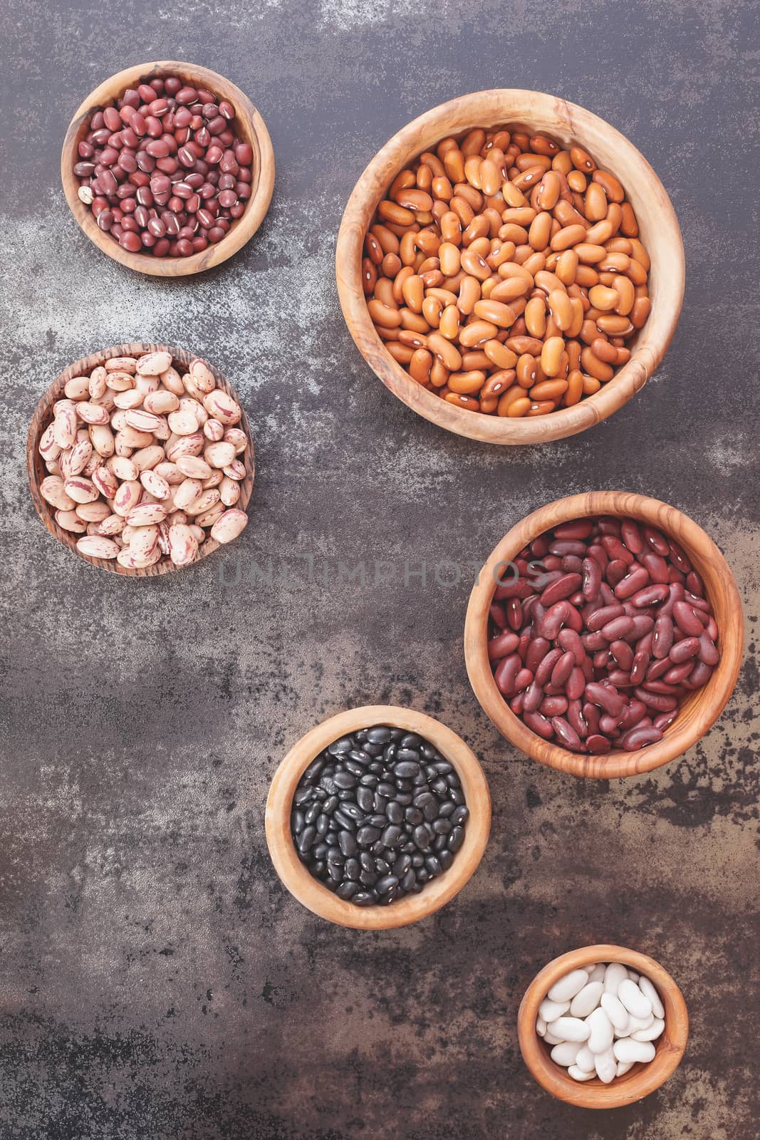 Still life of various types of dried beans in a wooden bowls. Top view, vintage toned image, blank space