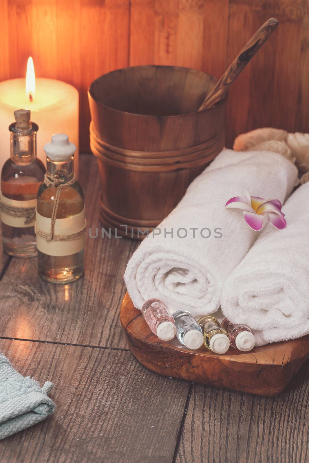 Spa treatment setting with frangipani, essential oil, scented candle  and towels for spa.  Macro selective focus with retro style processing, blank space Low light spa setting