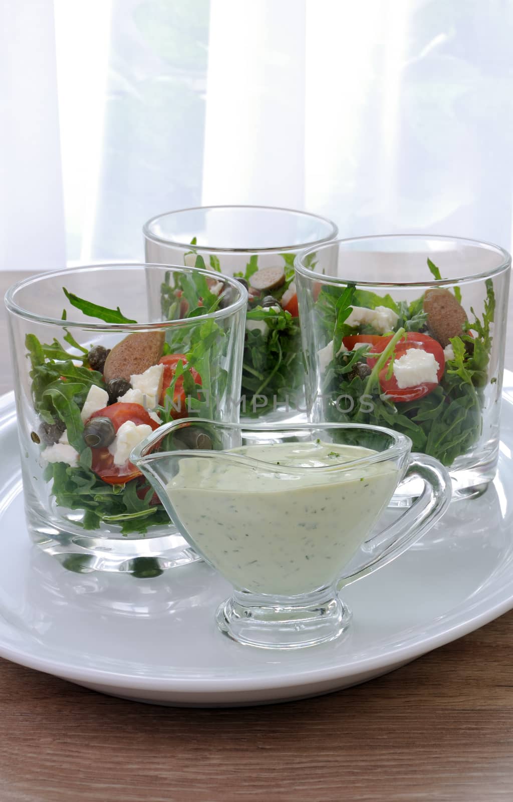 Mayonnaise sauce in a gravy boat with dill salad of arugula