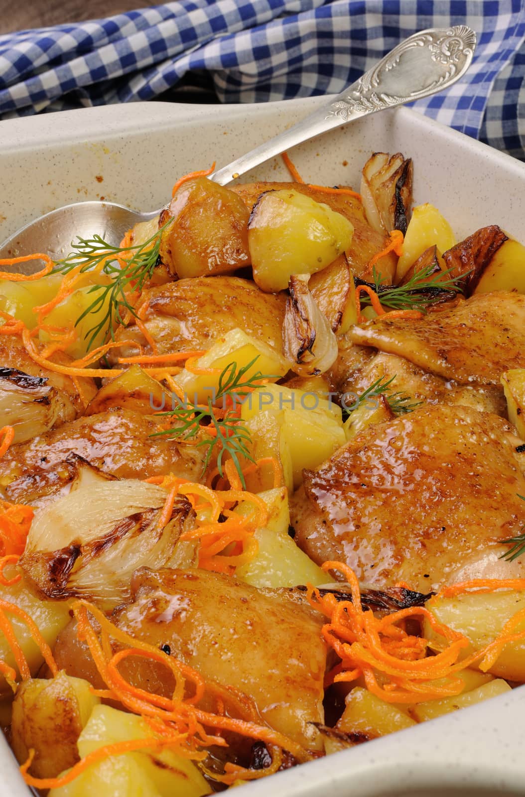 Braised roast chicken with potatoes, carrots and shalott in ceramic roasting pan