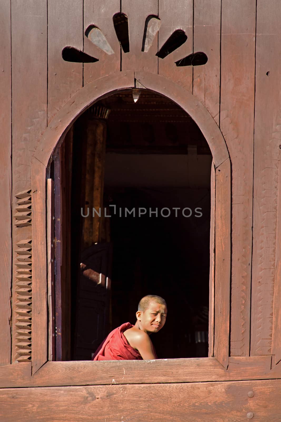 NLE,MYANMAR-Novemberl 24 : Young novice monk at window wooden Church of Nyan Shwe Kgua temple near Inle lake on November 24,2015 in Inle lake,Shan State ,Middle of Myanmar.