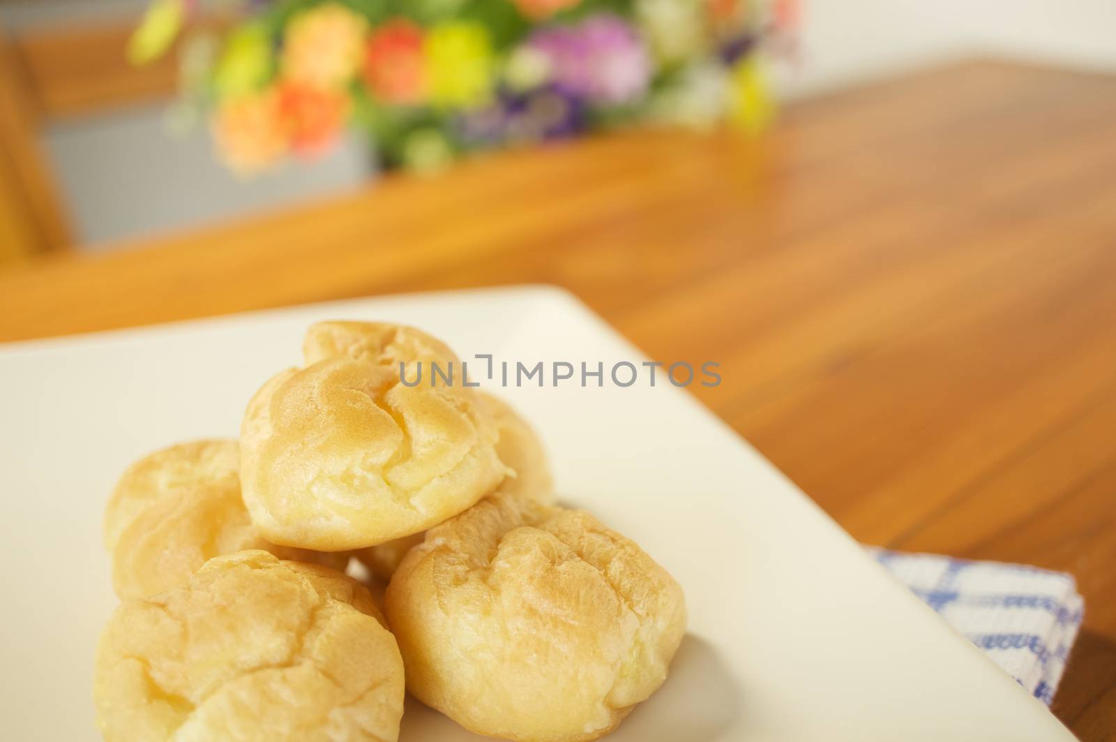 Eclair cream place in plate with blue fabric on wood table and blur flower as background.