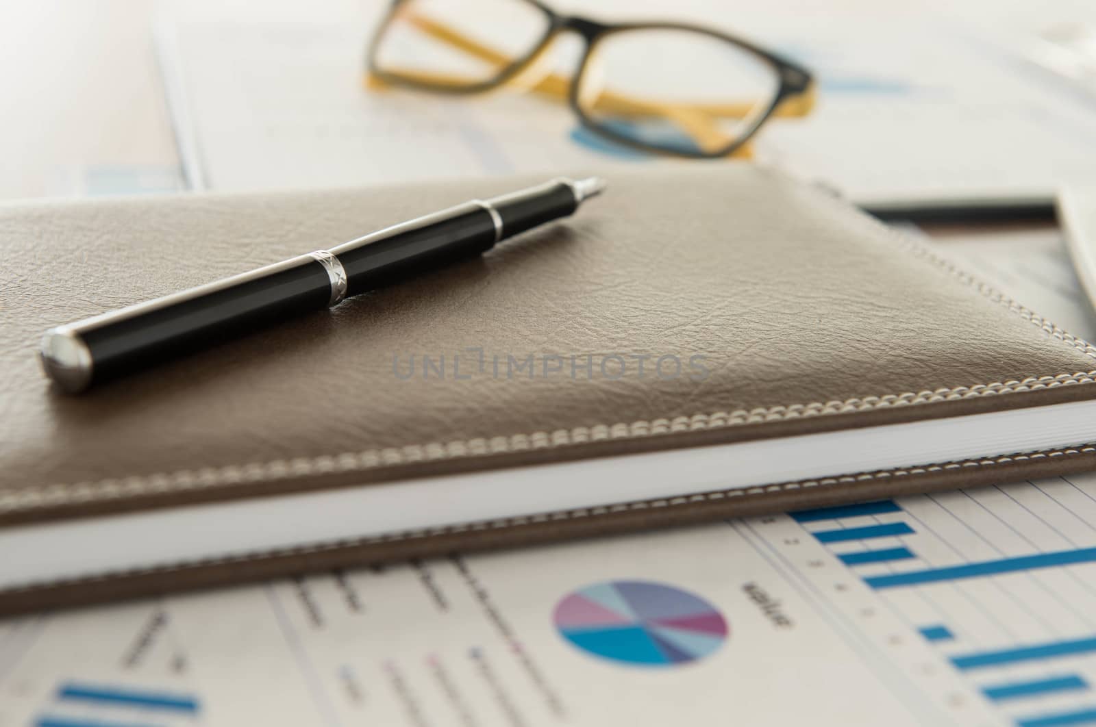 Marketer's desk with analysis Report , pen,book.