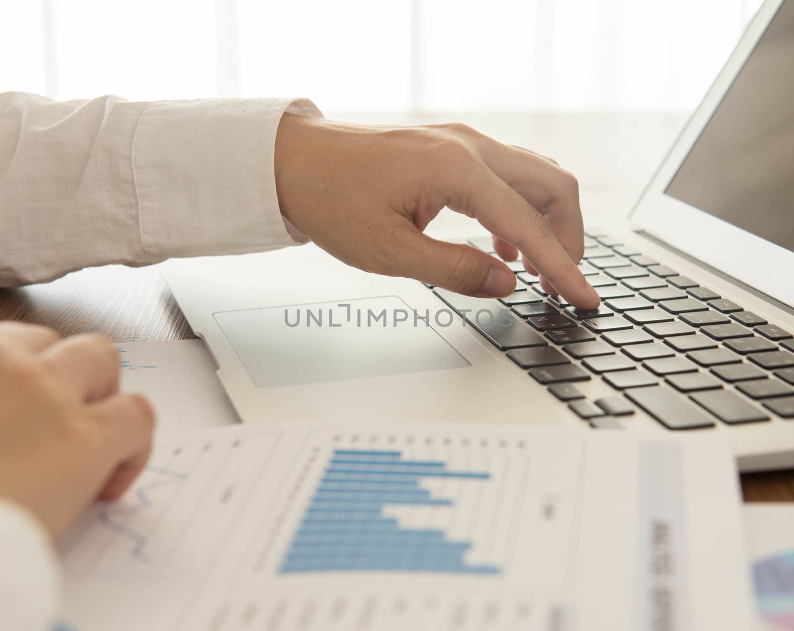 Businessmen are analyzing the data from laptop computer and report.