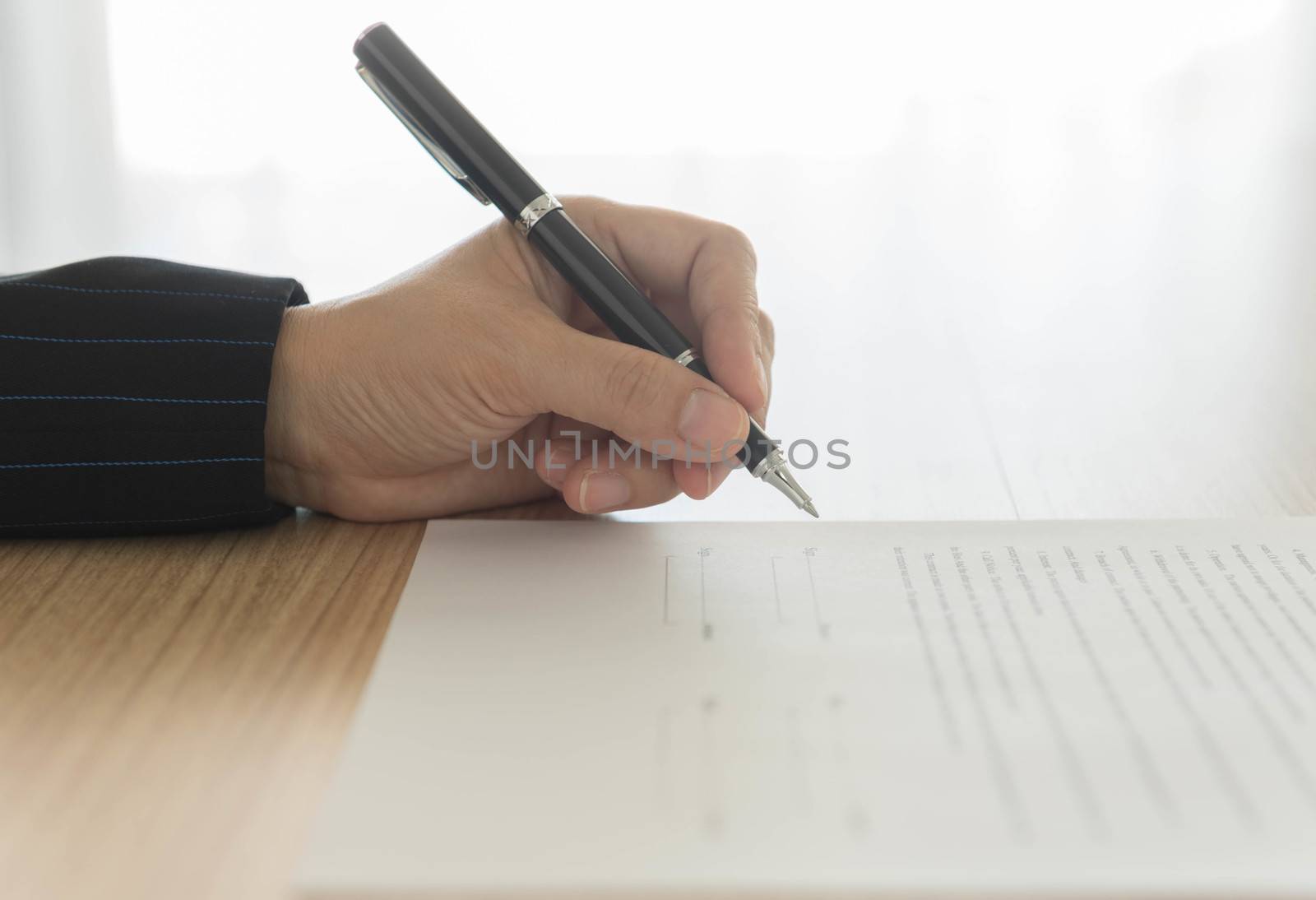 hand holding a pen to sign approval  about to sign a letter