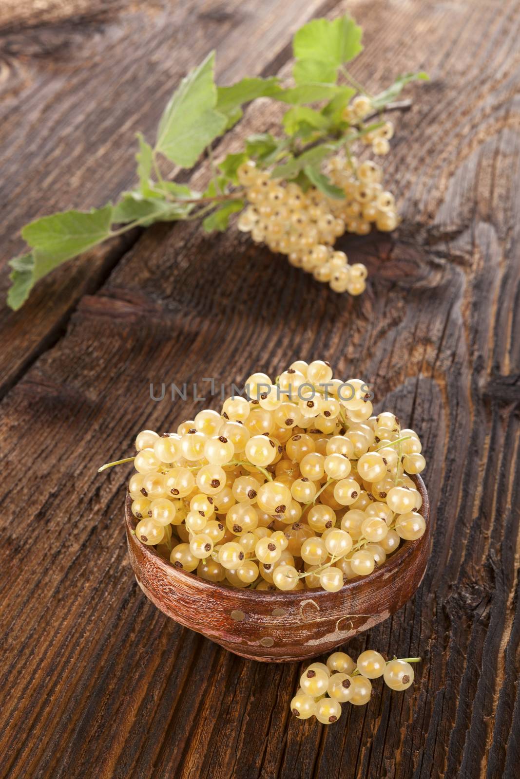 Ripe white currant in wooden bowl on old vintage wooden background. Healthy summer fruit eating. 