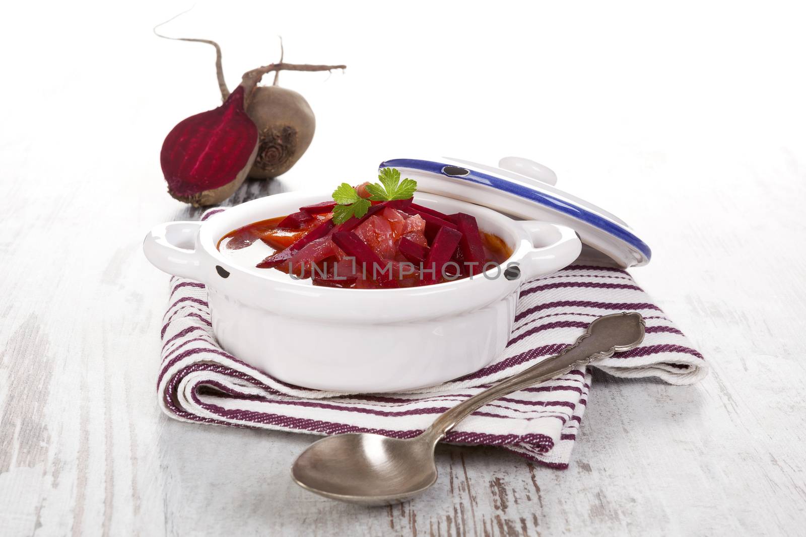 Delicious ukrainian borsch soup with fresh beetroot vegetable on purple cloth on rustic wooden table. Traditional european cuisine.