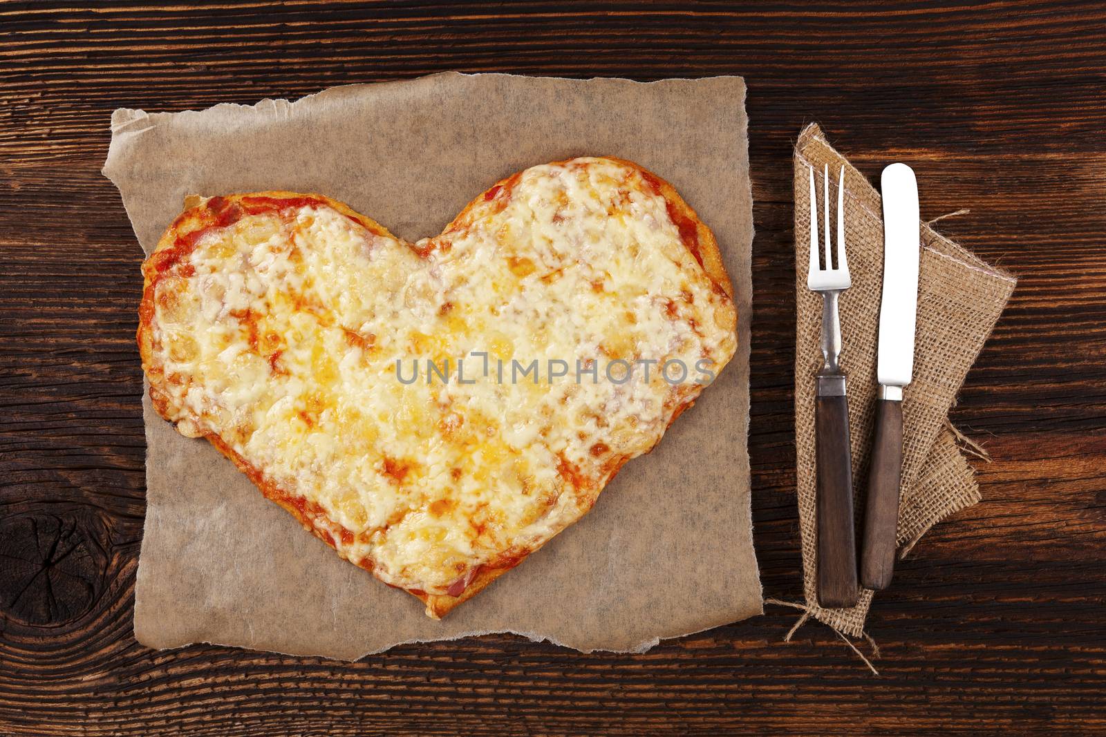 Delicious pizza in heart shape on wooden table, top view. Culinary pizza eating. I love pizza.