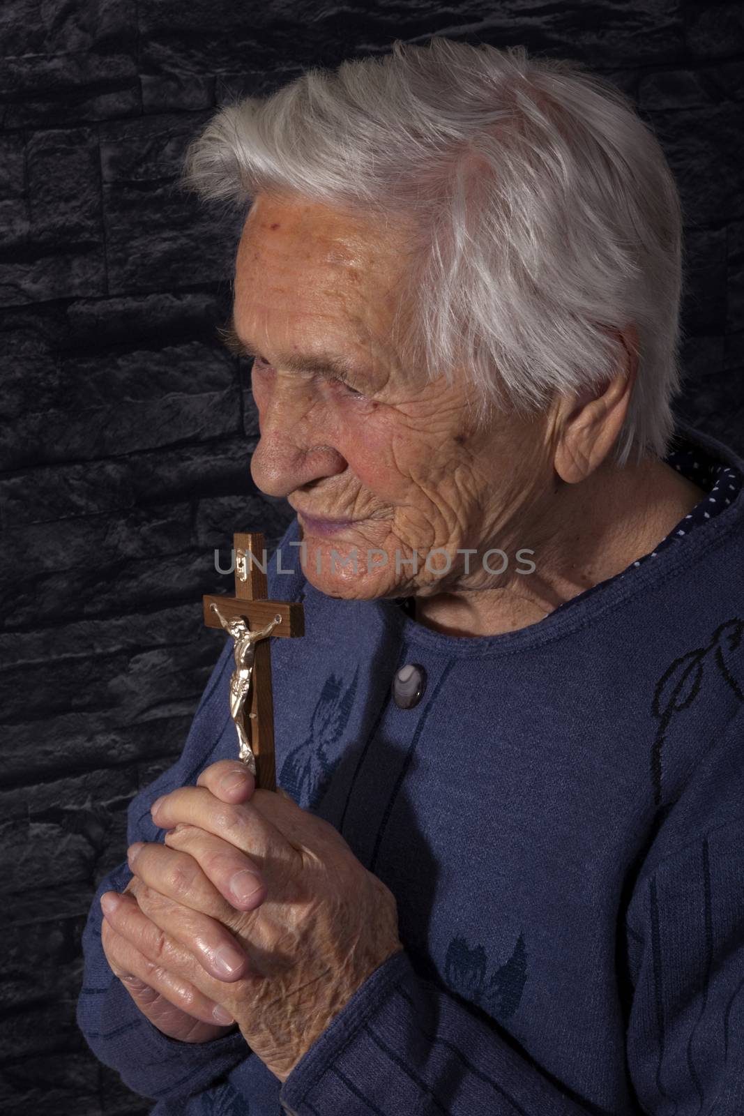Grandmother praying. Old wrinkled beautiful woman praying with rosary. Faith, spiritualy and religion.