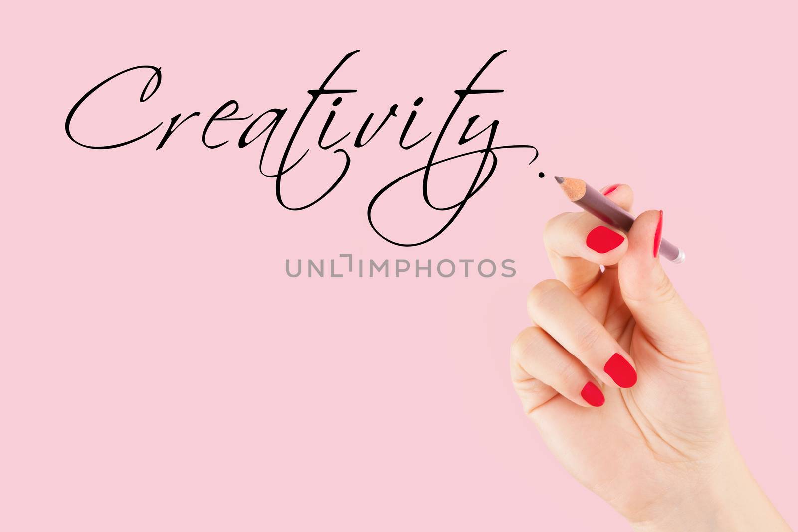 Creative industries. Female hand with pencil writing the word creativity in caligraphy.
