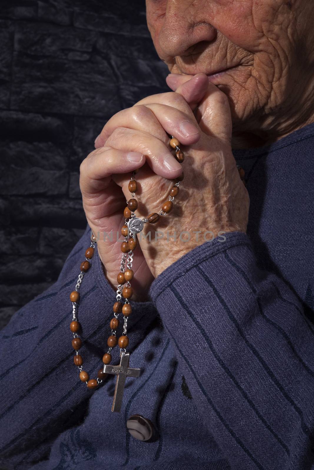 Grandmother praying. Old wrinkled beautiful woman praying with rosary. Faith, spiritualy and religion.