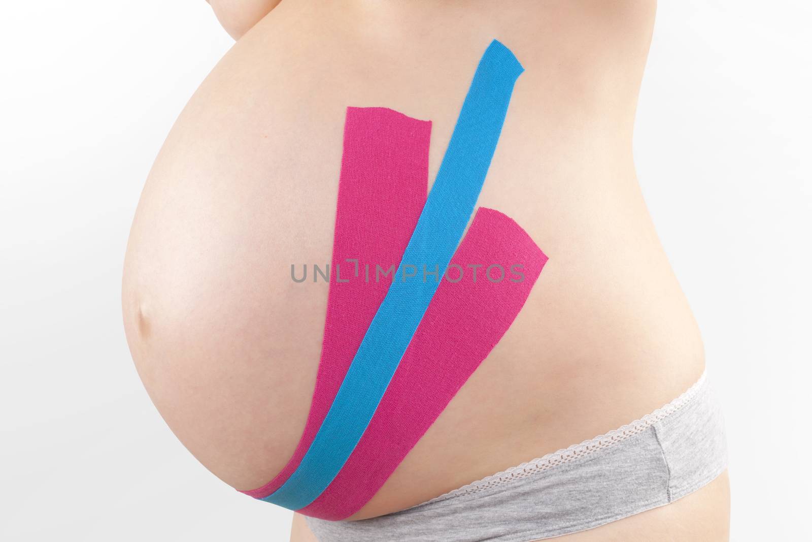 Beautiful pregnant woman with kinesio tape. Back pain in pregnancy, alternative kinesio tape therapy.