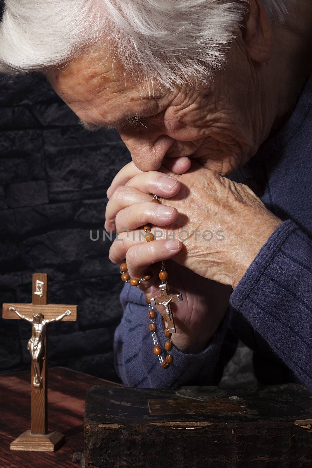 Grandmother praying. Old wrinkled beautiful woman praying with rosary. Faith, spiritualy and religion.