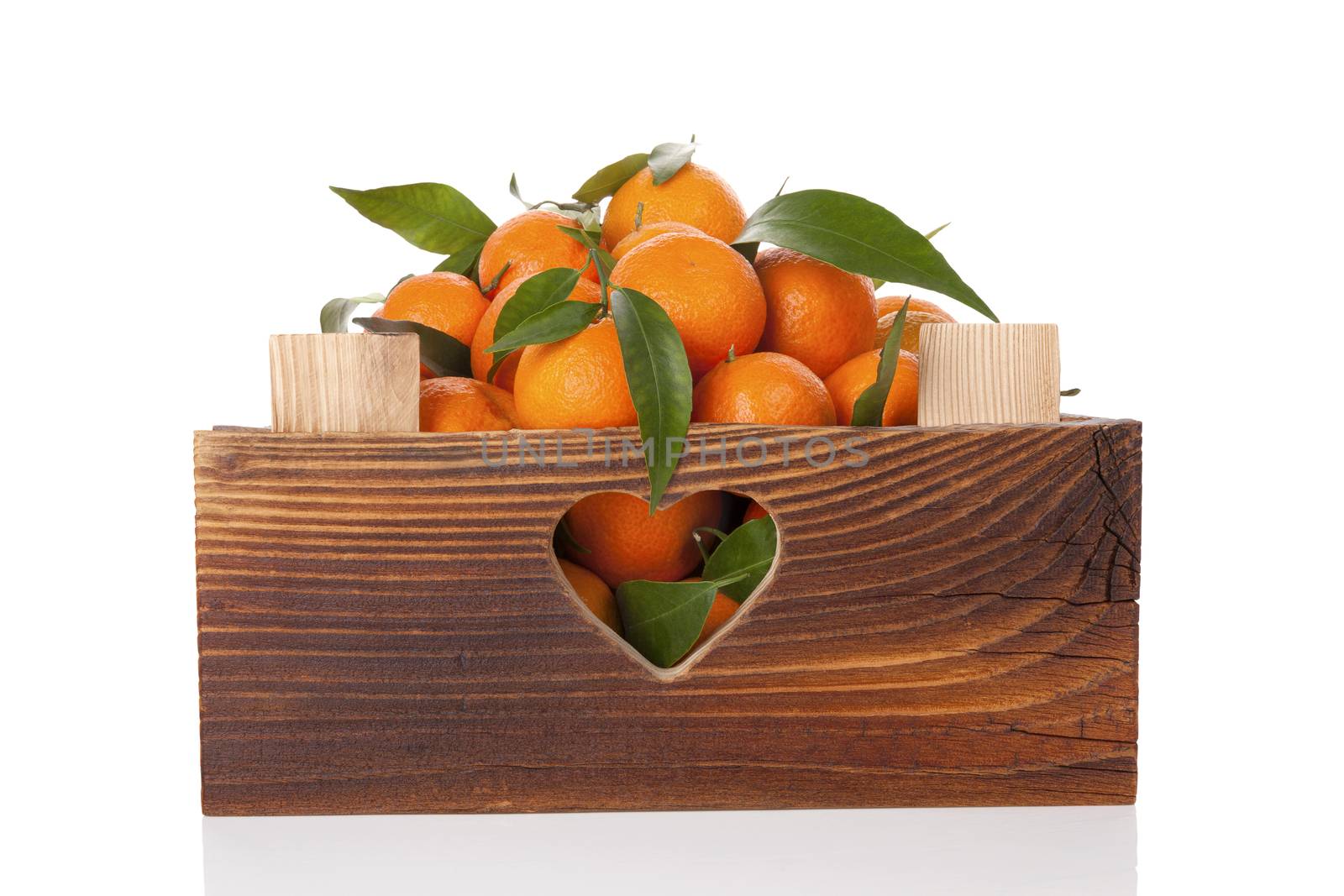 Fresh ripe mandarines with green leaves in wooden crate. Organic fresh mandarines, healthy fruit eating. 