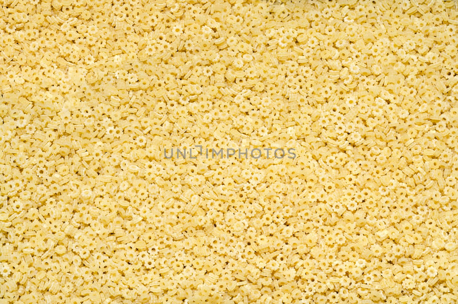 Textured background of small shaped pasta, scattered on the surface.