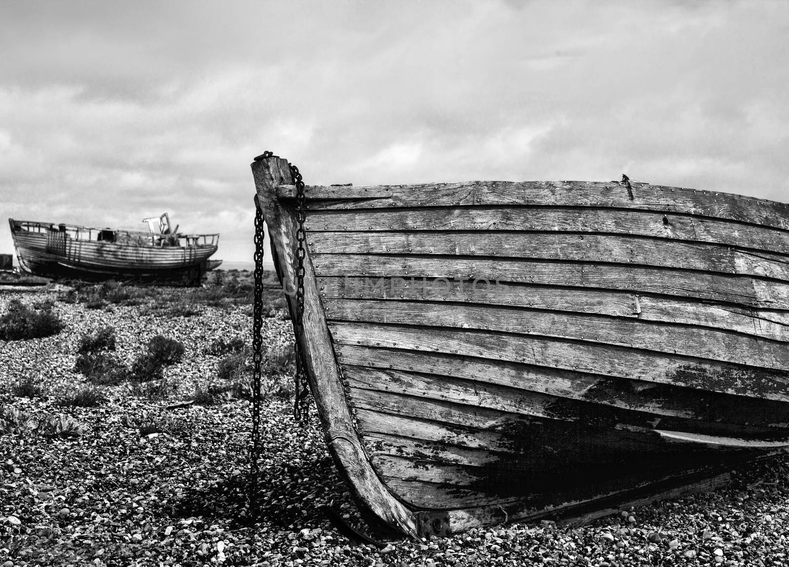 An old abandoned fishing boat stranded on a beech in black and white.