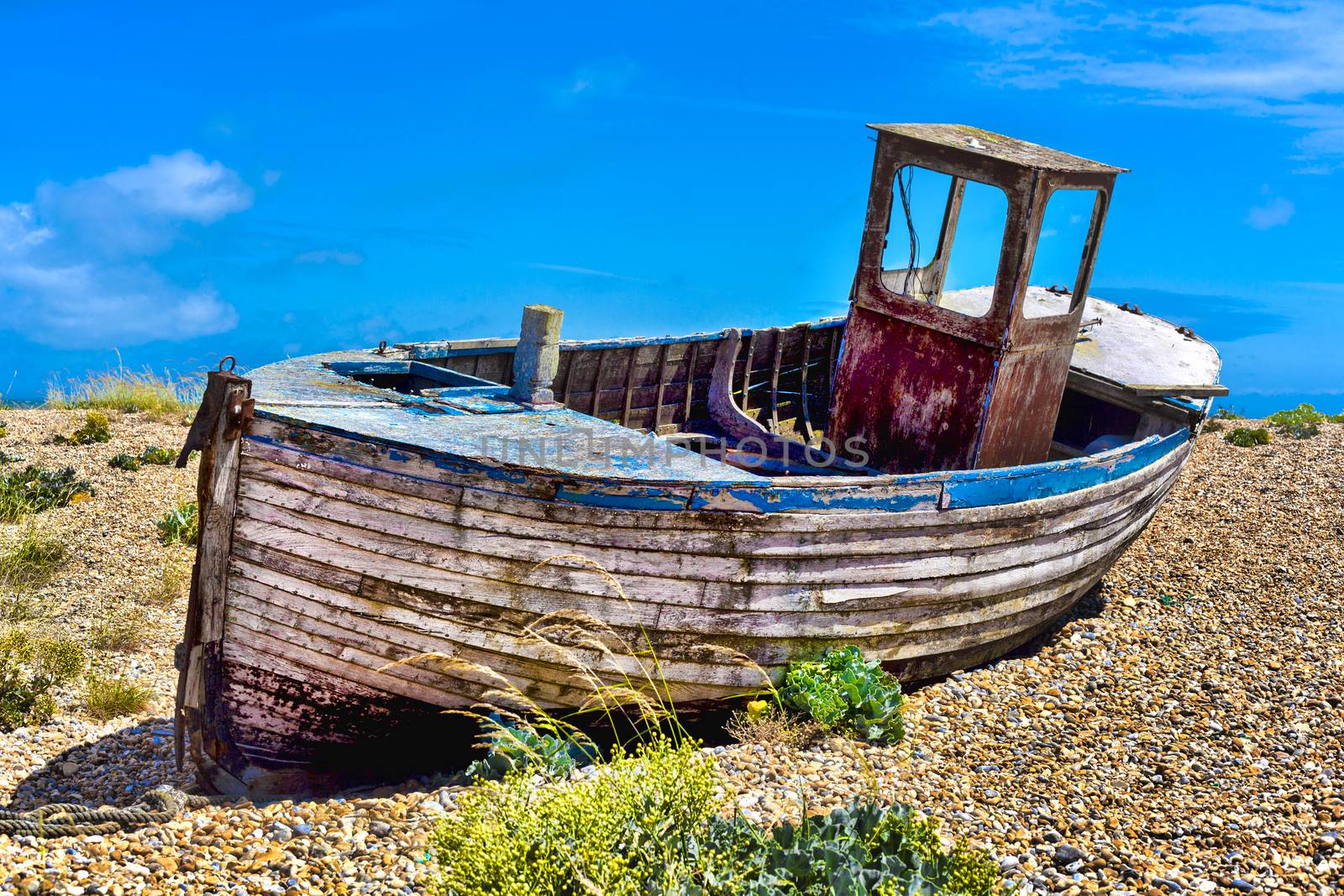 Old wooden fishing boat on a pebble beach.