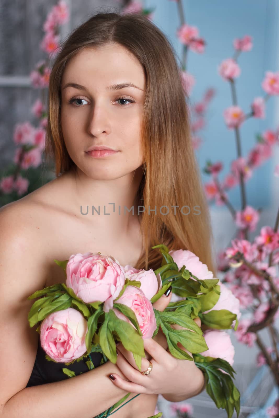 Beautiful close-up portrait of a young woman with peonies wreath. Spring natural care concept.