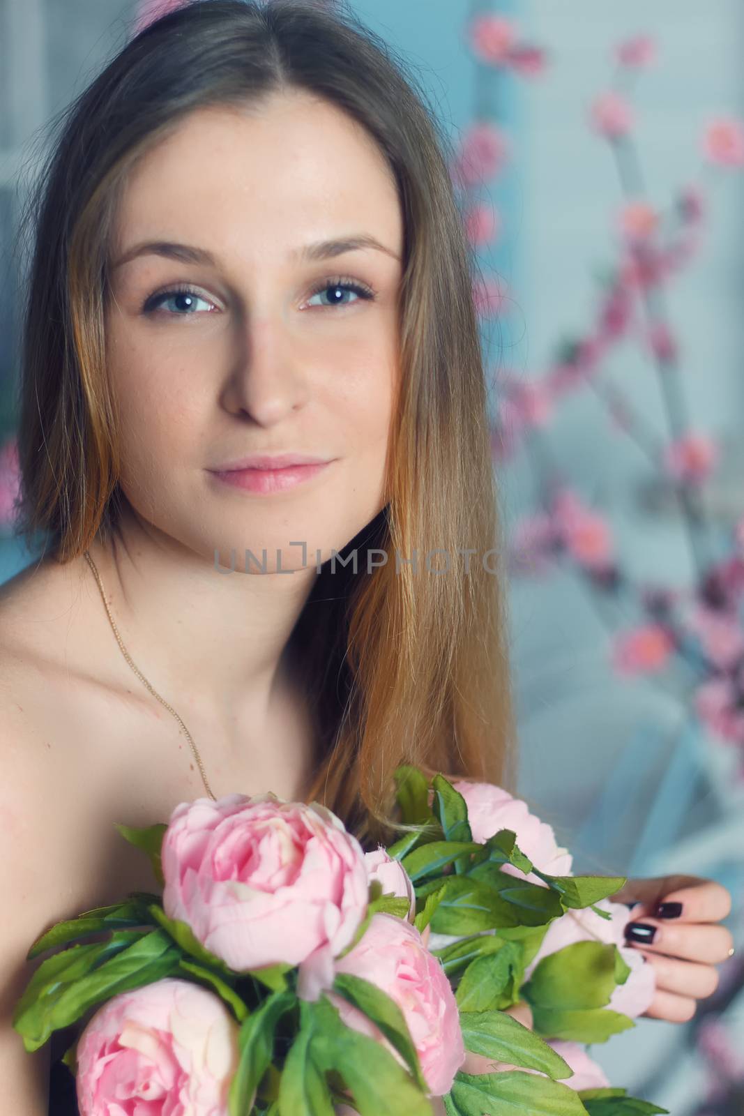 Beautiful close-up portrait of a young woman with peonies wreath. Spring natural care concept.