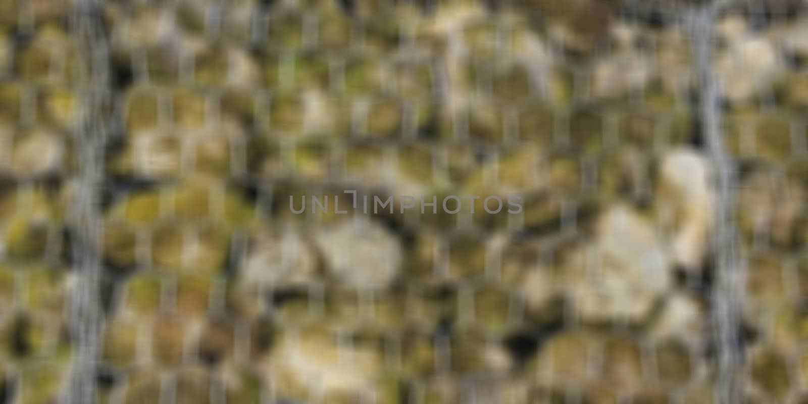 blur barrier built of small pieces of rock behind a fence of metallic mesh