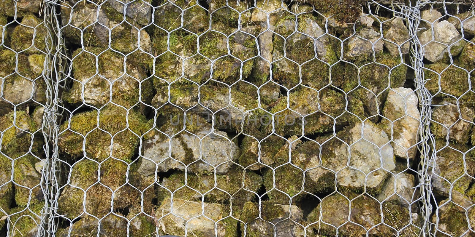 Closeup of a barrier built of small pieces of rock behind a fence of metallic mesh in thailand
