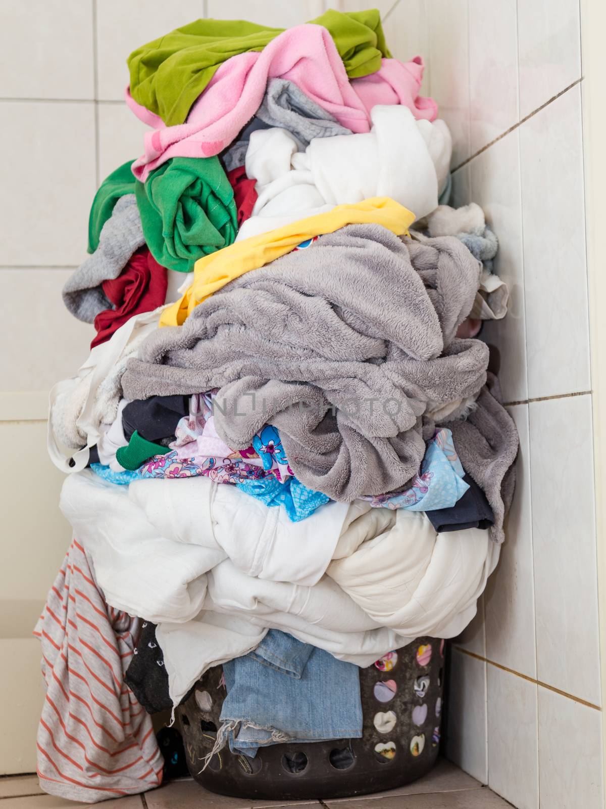 Laundr basket overflowing with dirty clothes and blankets