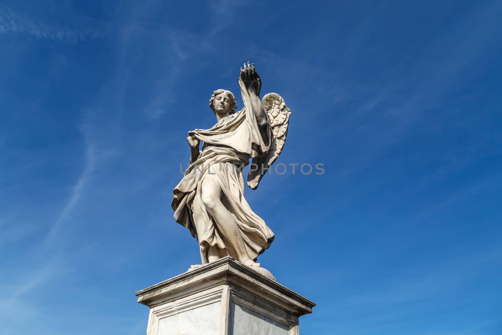 Close up detailed bottom view of a granit woman sculpture with wings, on bright blue sky background.
