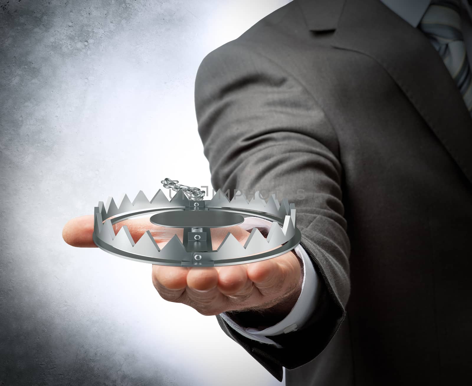 Businessman holding bear trap on grey wall background, danger concept