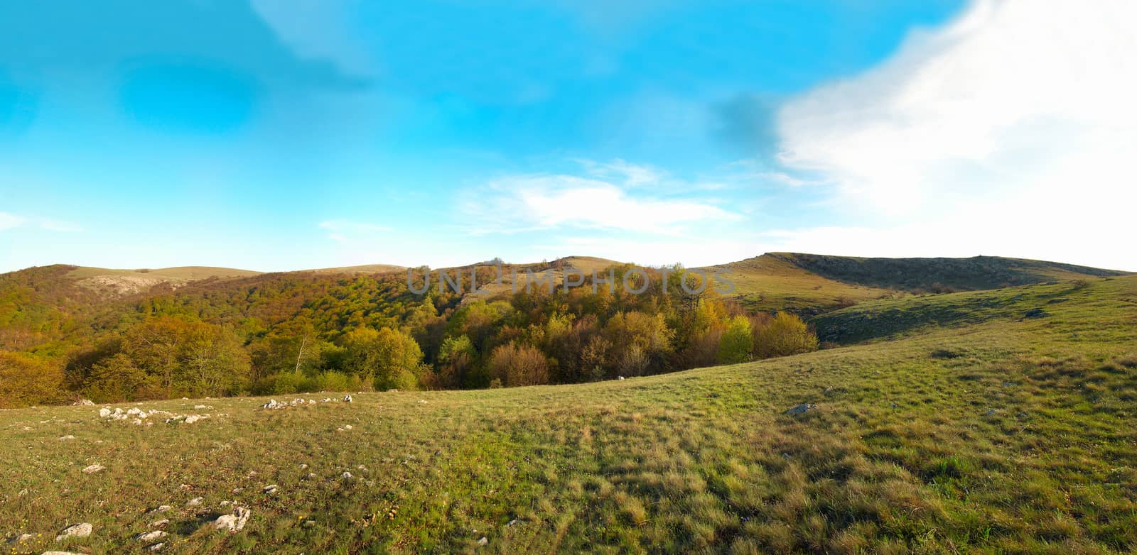 Panorama. Hills with cloudscape and blue sky.