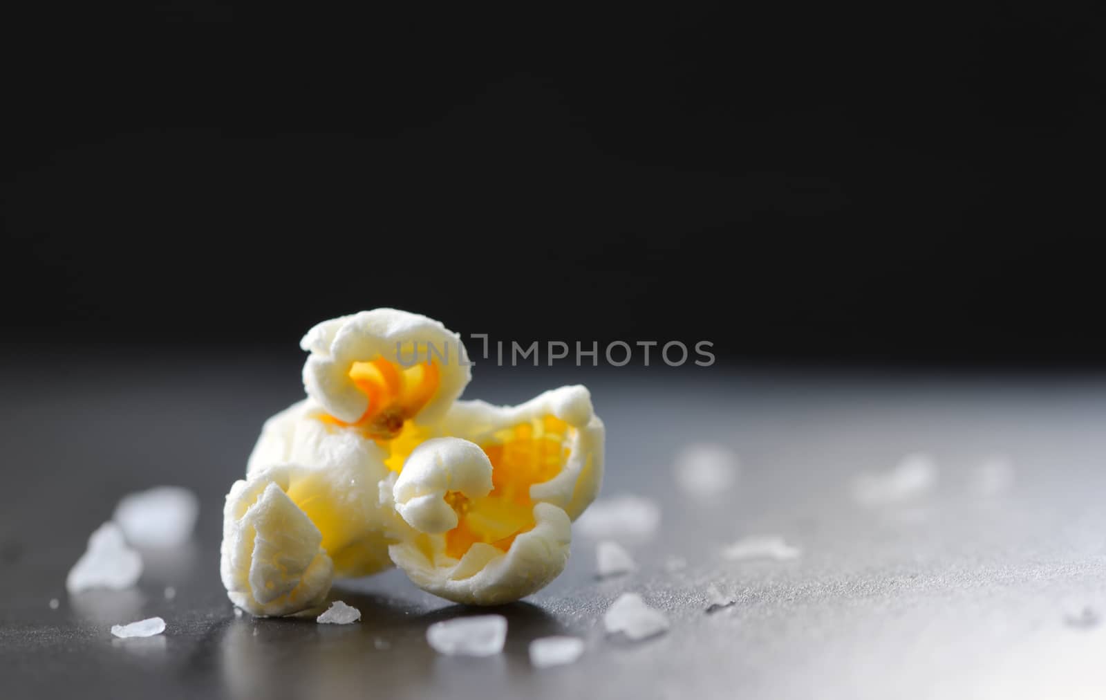 Single popcorn and salt isolated on black background